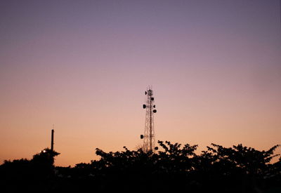 Silhouette of communications tower against sky at sunset
