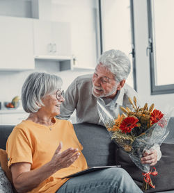 Side view of senior couple sitting on sofa at home