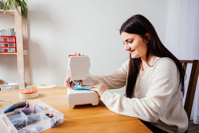 Young woman sewing at home