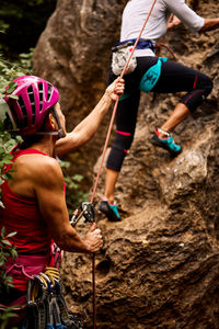 Low angle view of active senior male and female climbers climbing on rocky cliff