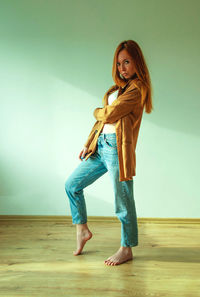 Portrait of young woman standing against wall