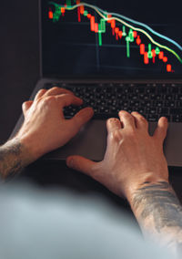 Cropped hand of man using laptop