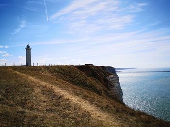 Lighthouse amidst sea and buildings against sky