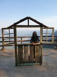 Portrait of woman sitting on railing against clear sky