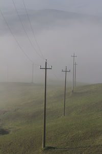 Electricity pylon on field against sky