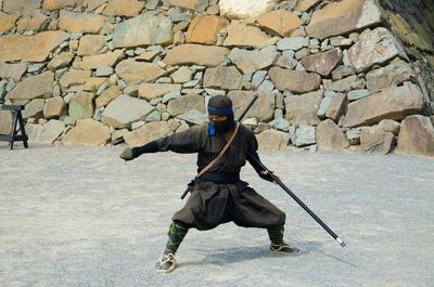 Rear view of man skateboarding on stone wall