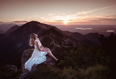 Woman on mountain against sky during sunset