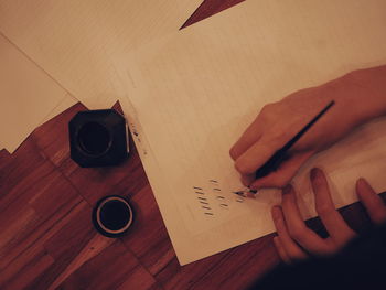 Cropped hands writing on paper at table