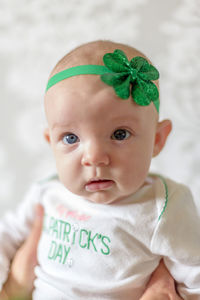 Cropped hand holding cute baby girl wearing green headband