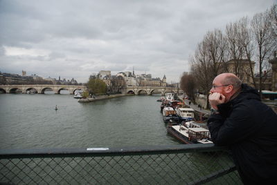 Man standing on bridge over river in city