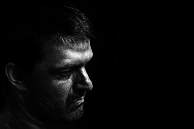 Close-up of man looking away against black background