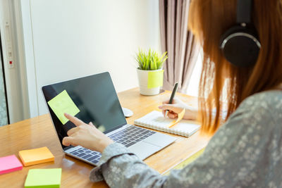 Midsection of woman using mobile phone while sitting on table