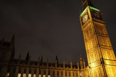 Low angle view of clock tower at night