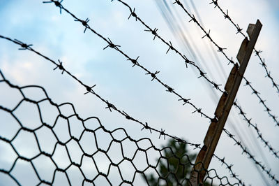 Low angle view of barbed wire fence against sky