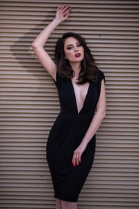 Portrait of beautiful young woman standing against wall