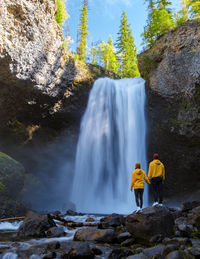 Rear view of man standing against waterfall