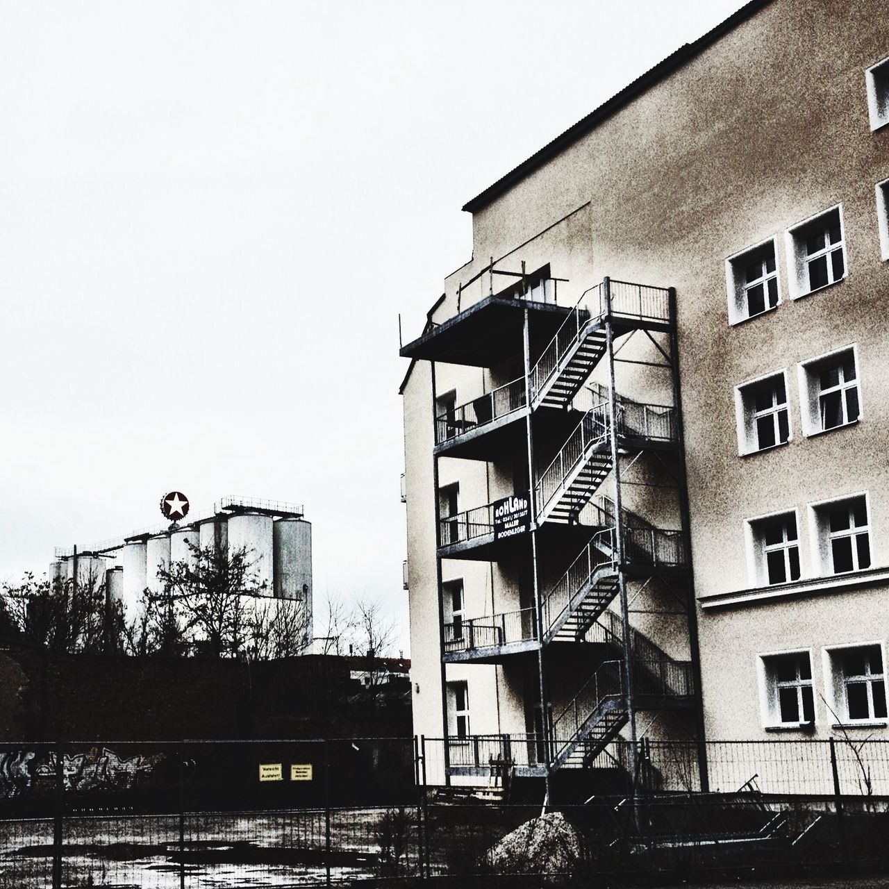 building exterior, architecture, built structure, low angle view, clear sky, residential building, building, window, residential structure, city, text, day, western script, communication, outdoors, graffiti, sky, no people, house, railing