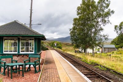 Railroad station platform by trees against sky