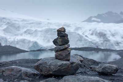 Stack of pebbles on snow against sky