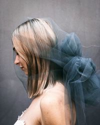 Close-up of woman wearing veil against wall