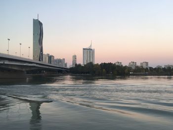 River in city against clear sky during sunset