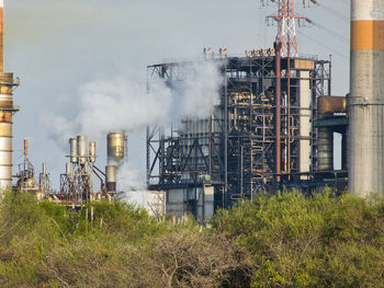 Smoke emitting from factory against sky