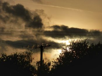 Low angle view of silhouette trees against cloudy sky