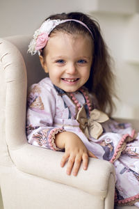 Portrait of cute girl sitting on sofa at home