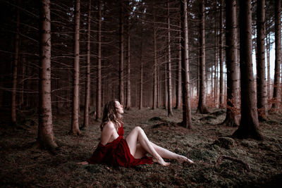 Full length of woman sitting in forest