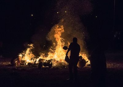 Silhouette man standing by bonfire at night