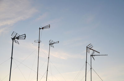Low angle view of antennas against sky during sunset