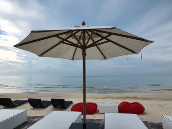 Deck chairs on beach against sky