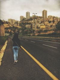 Rear view of woman walking on road in city