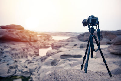 Tilt image of camera on beach against sky during sunset