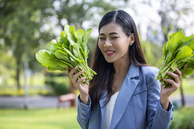 Portrait of young woman holding plant