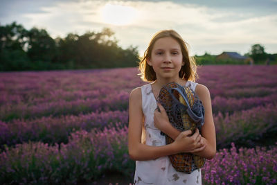 Girl holds net bag with bottle of water and french baguette in lavender field. summer travel