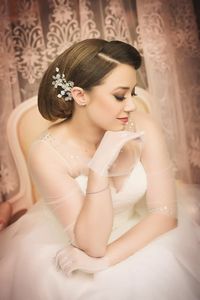 High angle view of beautiful bride sitting on chair against curtain