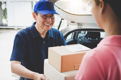 Smiling delivery man giving box to customer