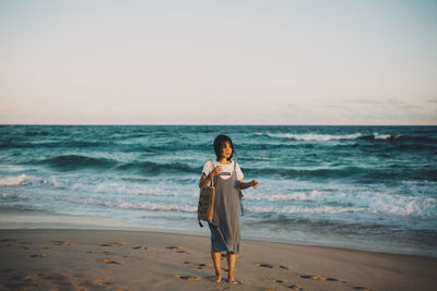 Full length of woman standing on beach against sky