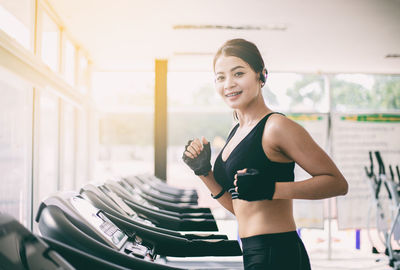 Portrait of smiling young woman running on treadmill