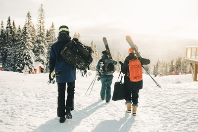 Full length rear view of friends walking at ski resort during winter