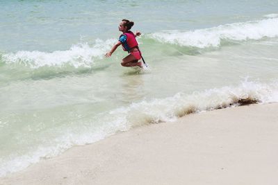 Side view of girl with arms outstretched standing in sea