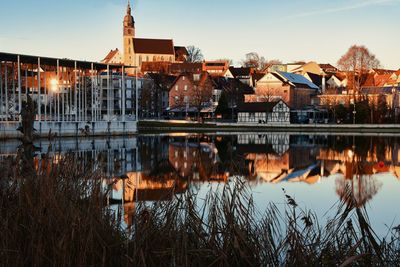 Buildings by lake against sky in city