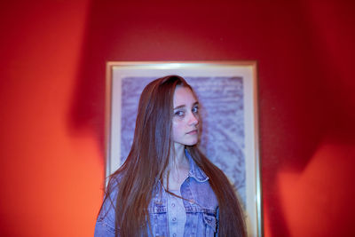 Portrait of woman standing against picture frame and wall