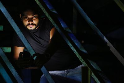 Portrait of young man in front of metal gate at night