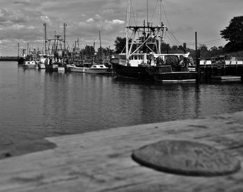 Boats moored at harbor against sky