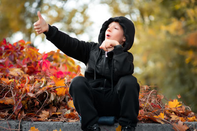 Boy standing by leaves during autumn