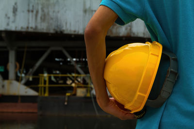 Midsection of man holding hardhat