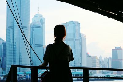 Rear view of woman on boat looking at modern buildings in city