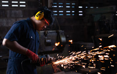 Side view of welder welding metal in workshop